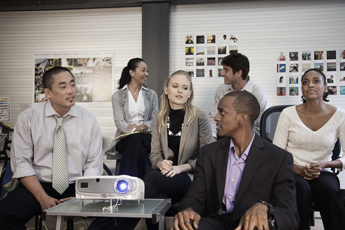 Business people using projector in conference room